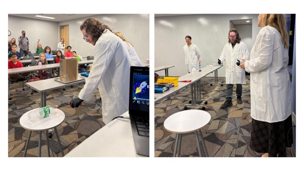 Two scientists in lab coats conduct a science demonstration in front of an audience in a classroom, with various materials and equipment on tables.