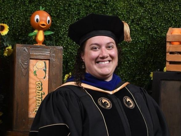 A person in a graduation gown smiles.