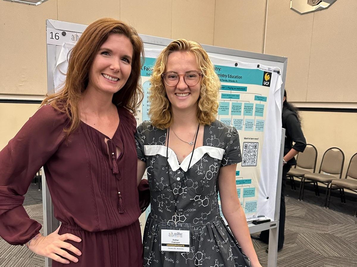 Two women standing in front of a poster board.