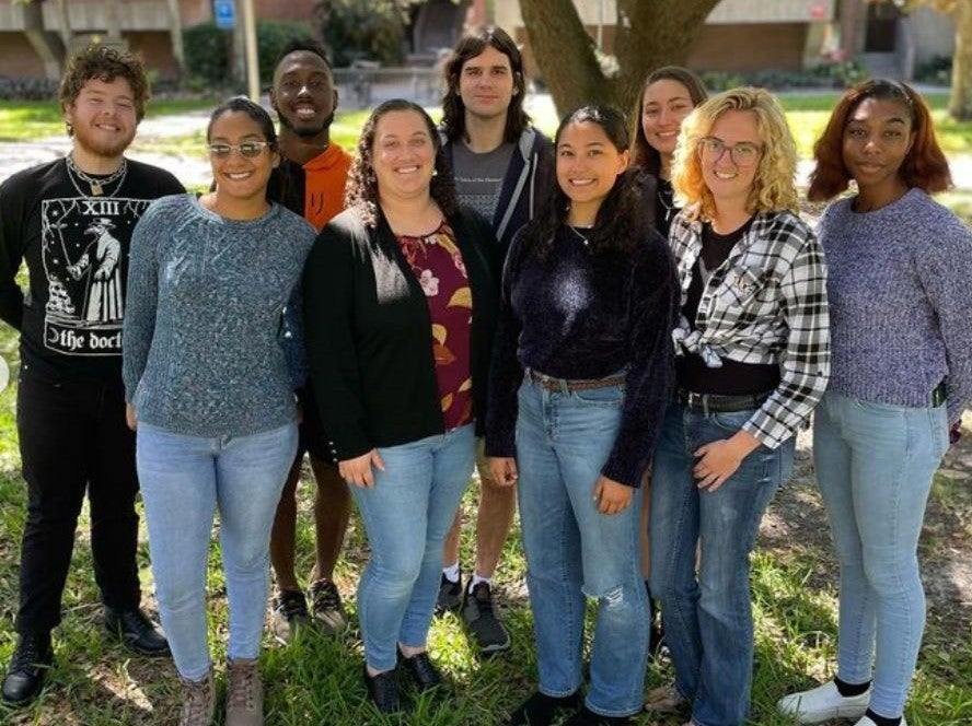 A group of people standing in front of a tree.